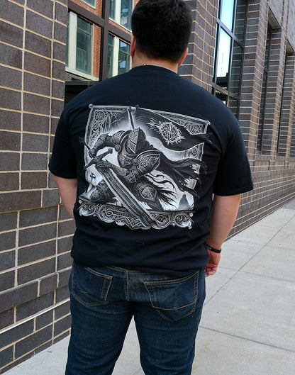Person wearing a black t-shirt with a graphic design on the back, standing against a brick wall.